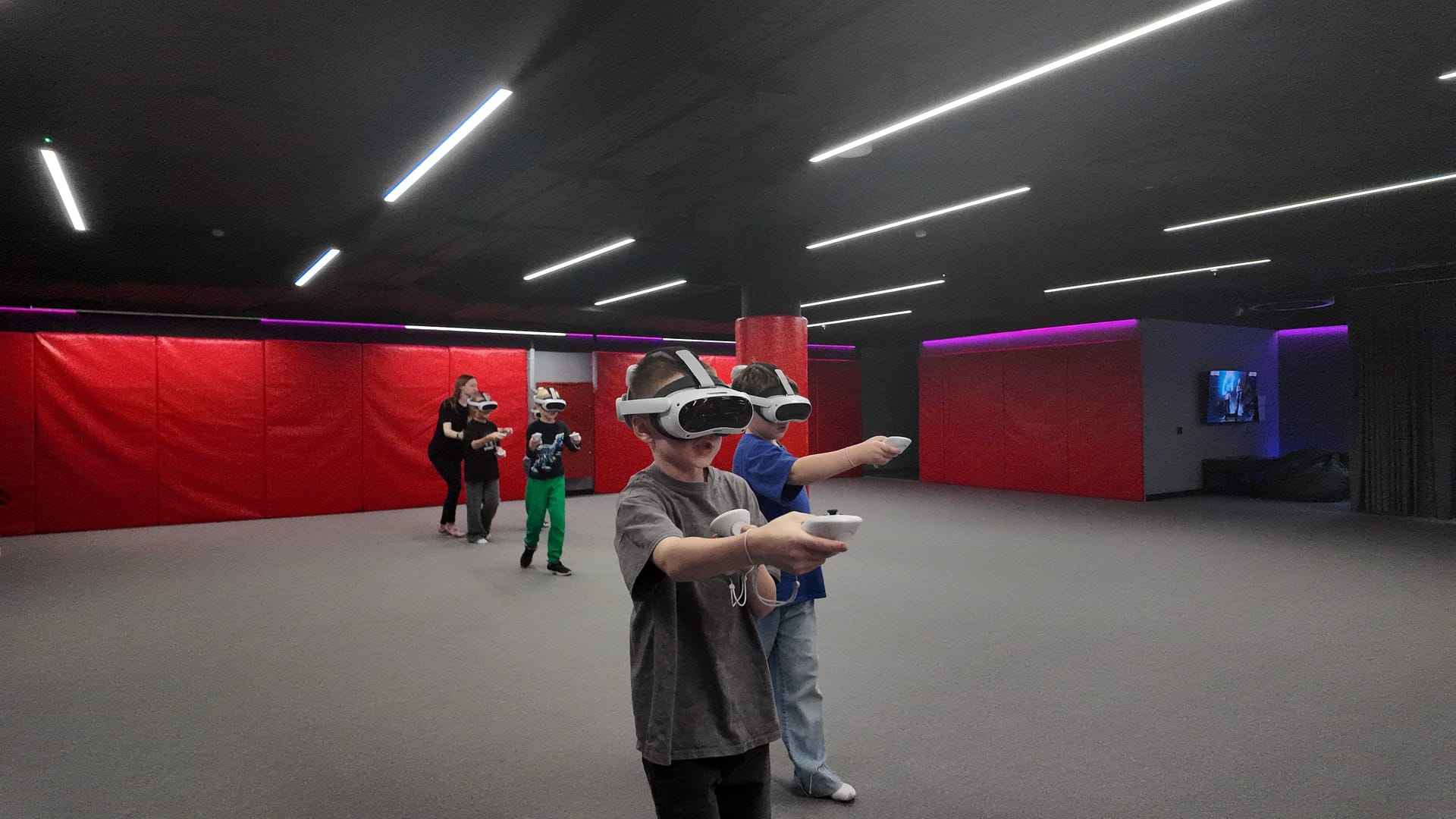 Дети в VR-шлемах целятся контроллерами на VR-арене